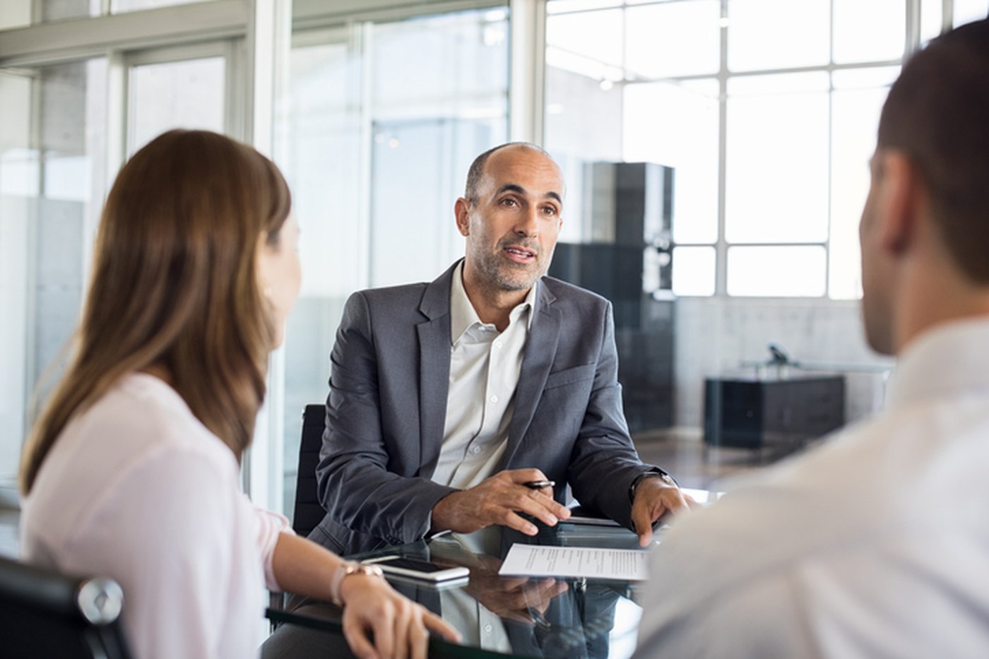 A financial advisor talking with two practice owners across a conference table